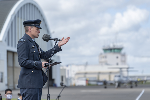 Air Force member addressing a gathering outside a hangar