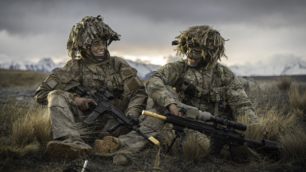 Two NZDF soldiers training in open terrain with mountains in the background