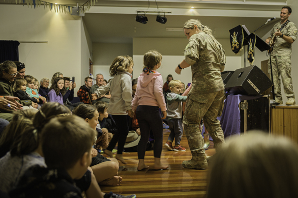 NZDF personnel performing and dancing with children in a hall